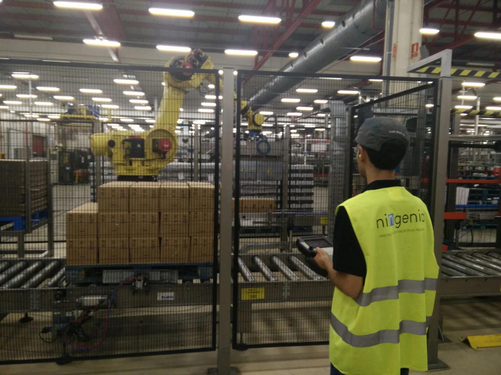 Operario supervisa robot industrial junto a cajas en fábrica