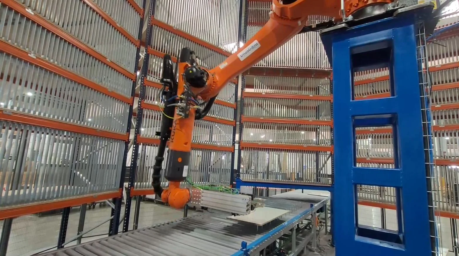 Brazo robótico naranja junto a cinta transportadora industrial
